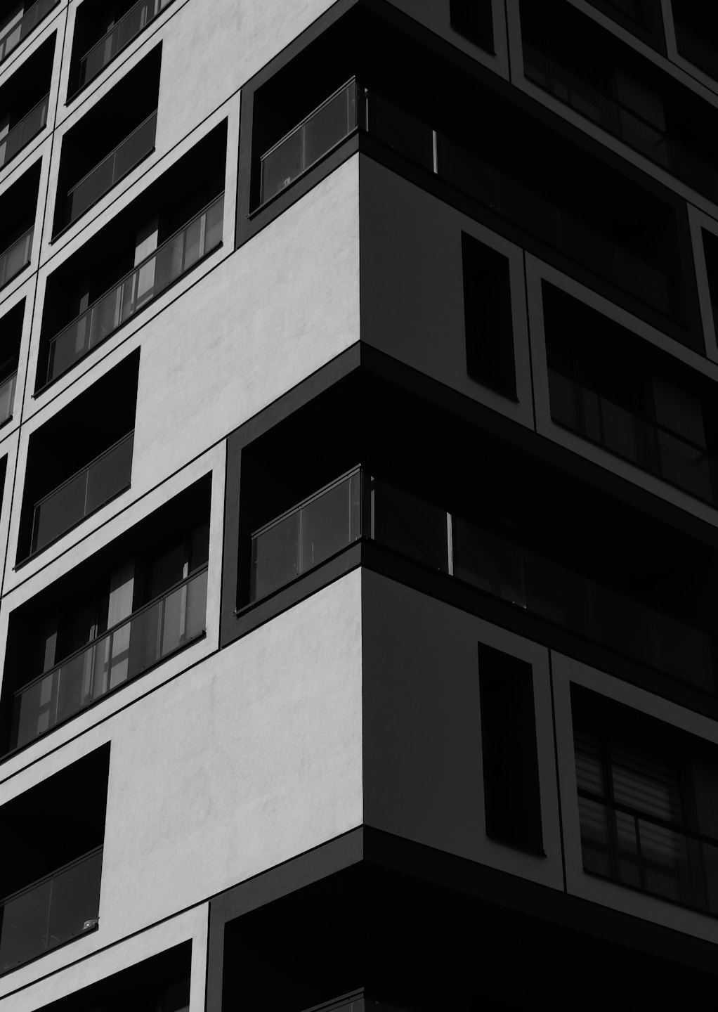Facciata di un moderno edificio in cemento con motivi geometrici e balconi in vetro.
